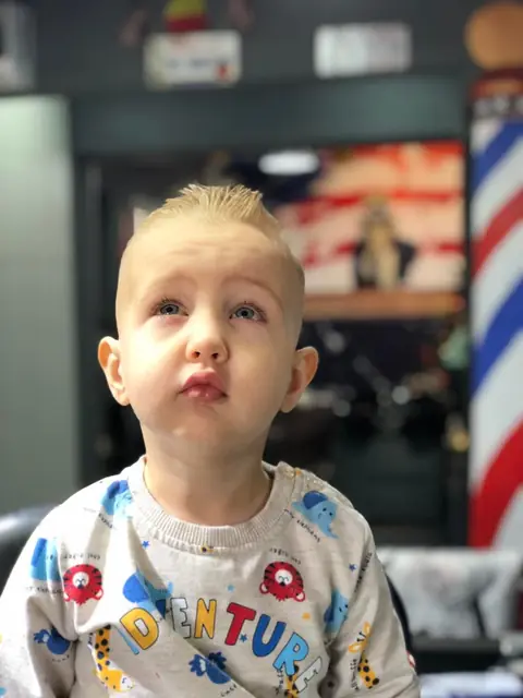 Băiețel blond cu creștet ridicat, după tuns