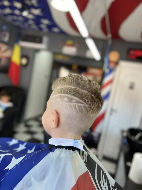 Băiat cu fade și model desenat pe lateral, din spate