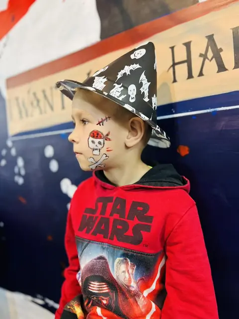 Băiat cu pălărie de vrăjitor și față pictată, la Halloween