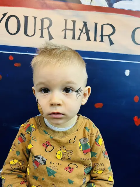 Băiețel blond cu tunsoare scurtă și față pictată