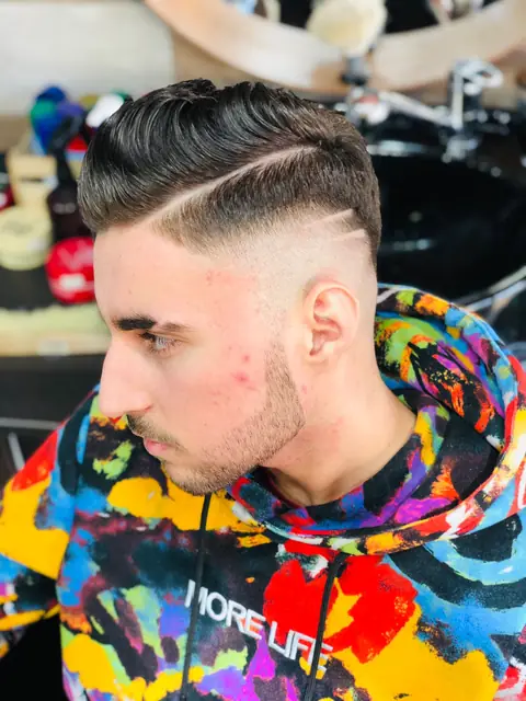 Tânăr cu pompadour, fade și cărare desenată, din profil